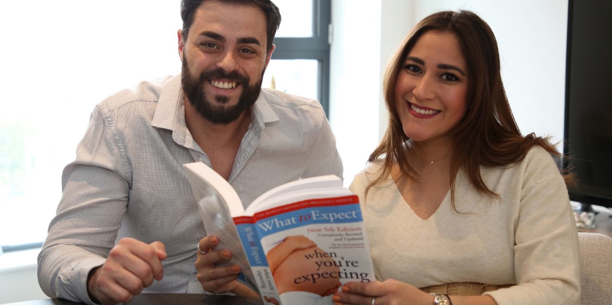 Terence and Tamara with a 'What to expect when you're expecting' book in their kitchen.